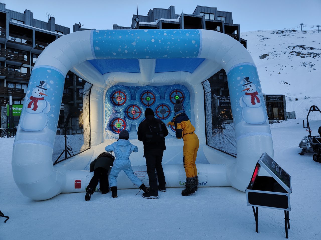 Cage Neige Interactive en station de ski : une famille vise les cibles lumineuses avec des boules de neige